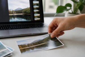 Hand die een foto plaatst naast een laptop met een beeldvoorbeeld